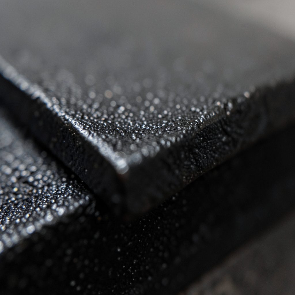 Extreme close-up of dark cast iron surface with machined edge, subtle metallic sheen